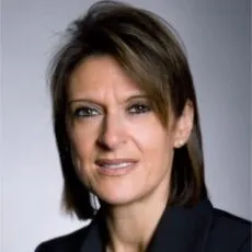 Gail Rifkind, head and shoulders, in a dark jacket against a grey studio ground.